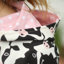 Load image into Gallery viewer, Close-up of a hood with a black and white cow print on the outside and a pink lining with white stars