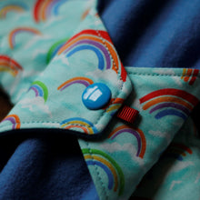Load image into Gallery viewer, close up of the rainbow pattern pad showing the sewing quality of the pad and a blue plastic snap
