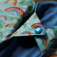 Load image into Gallery viewer, Close up of a rainbows daily liner showing the sewing finish on the edges of the pad and the blue plastic snap.