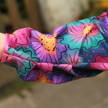 Load image into Gallery viewer, A close-up of a colorful floral-patterned sleeve with a blurred outdoor background.
