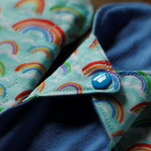 Load image into Gallery viewer, Close up of a rainbows daily liner showing the sewing finish on the edges of the pad and the blue plastic snap.
